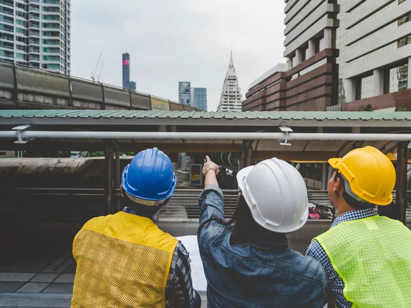 Construction team in hard hats surveying a city site