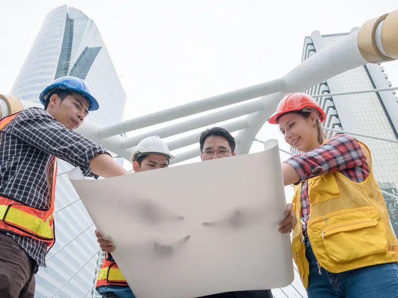 Engineers in hard hats reviewing a blueprint