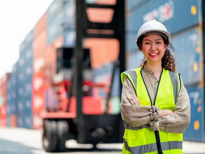 Logistics worker in a safety vest at a container yard