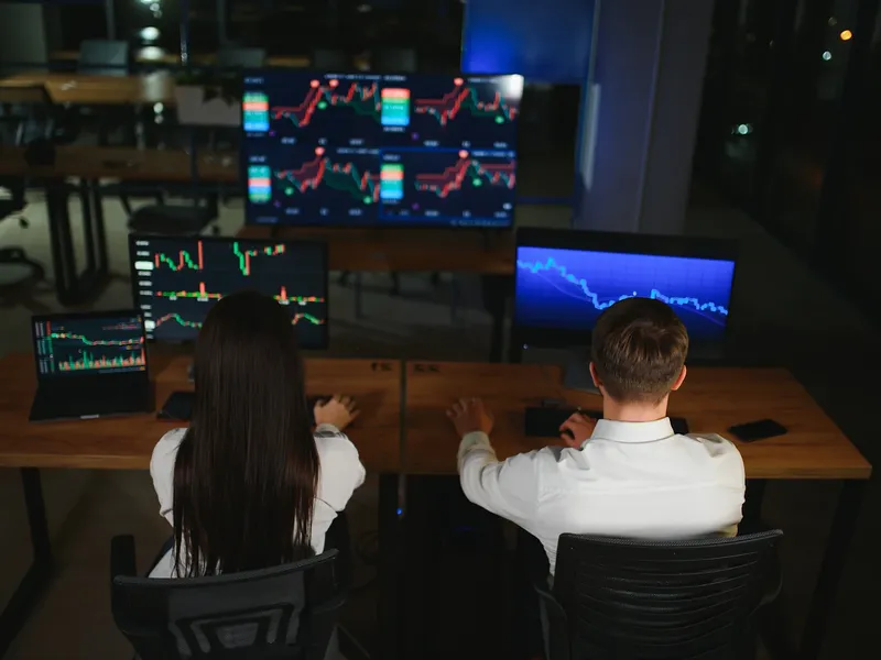 Traders working at desks with market charts on screens